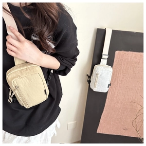 Detailed view of minimalist nylon crossbody bags in beige and white with front zippers