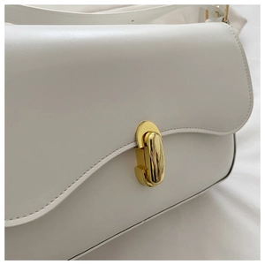Close-up of white minimalist crossbody bag featuring a golden oval twist lock clasp