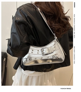 Close-up of metallic silver crescent bag with punk style buckles and eyelets detail