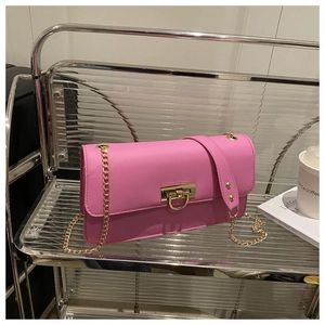 Détail d'un sac porté épaule en cuir rose avec chaîne dorée et fermoir pivotant