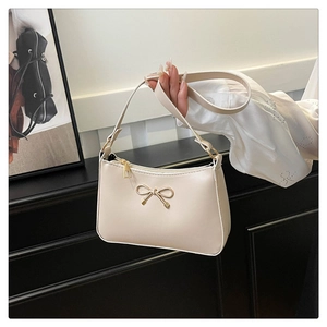 Detail view of cream white shoulder bag with golden bow buckle and smooth PU texture