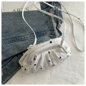 Détail du sac bandoulière blanc en tissu gaufré à fleurs noires avec texture plissée