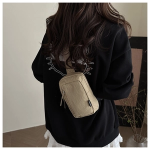 Detail of khaki nylon chest bag showing crinkled texture and fashion brand label