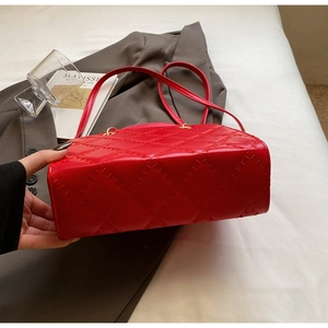 Detail of red quilted leather handbag with gold hardware against a stylish office backdrop