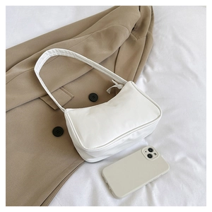 Mini white underarm bag shown next to a smartphone for size perspective and scale