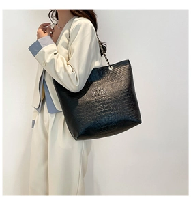 Detailed macro view of black crocodile pattern leather tote with golden chain strap
