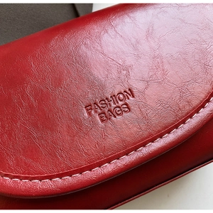 Macro view of red leather texture with FASHION BAGS embossing and white stitching