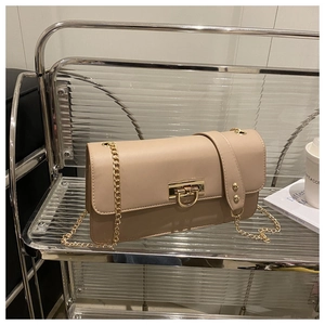 Détail du sac beige avec bandoulière chaîne dorée et boucle sur une étagère chic
