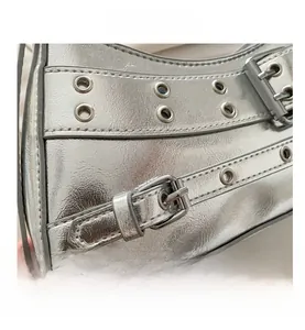 Detailed close-up of metallic silver shoulder bag with eyelet studs and buckle design