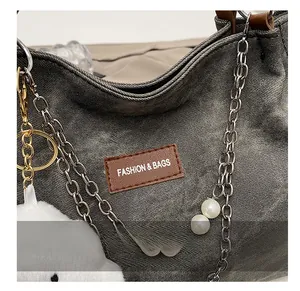 Detailed macro view of dark grey denim tote with pearl chain and fashion leather tag