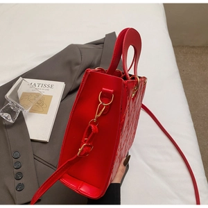 Macro view of red patent leather bag showing quilted diamond pattern and gold hardware