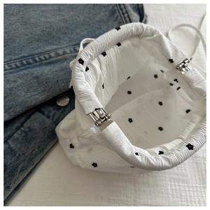Détail de l'intérieur d'un sac bandoulière blanc à fleurs avec fermoir métallique argenté