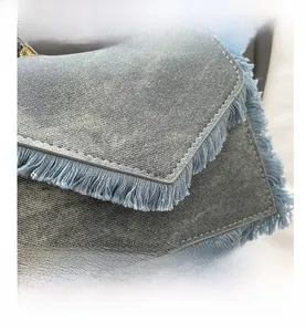 Close-up of washed blue denim mini bag showing fringe edges and fine stitching details