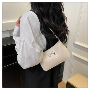 Close-up of cream PU hobo bag featuring a decorative golden metal bow on the shoulder strap
