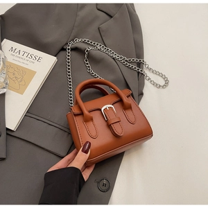Détail du mini sac à main caramel avec texture cuir, chaîne argentée et boucle décorative
