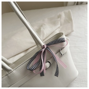 Détail d'un cabas en cuir blanc orné d'élégants nœuds en ruban rose et à carreaux vichy