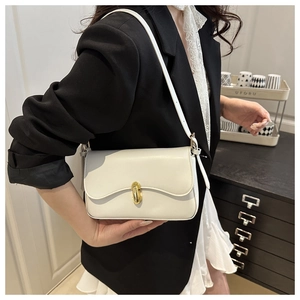 Detail of minimalist beige leather underarm bag with gold metal twist lock and flap
