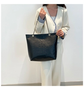 Close-up of black crocodile embossed tote bag with gold chain strap detail