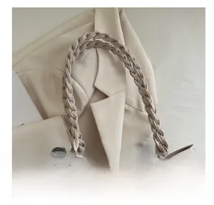 Detail of beige woven tote bag with braided handles and blue floral scarf accessory
