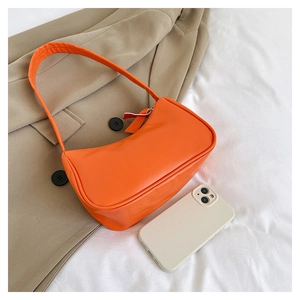Mini orange PU leather hobo bag on white cloth with smartphone for size reference