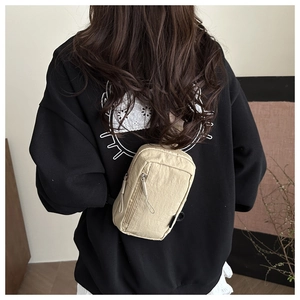 Detail view of the beige nylon chest bag showing multiple zipper pockets on back model