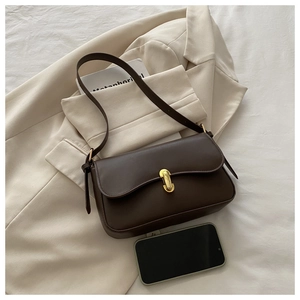 Detail view of a vintage brown leather crossbody bag with gold buckle and phone for size