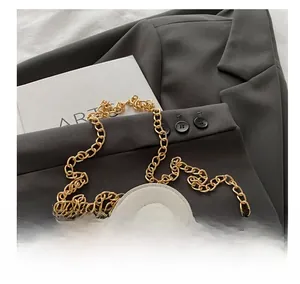 Détail du sac cylindrique en cuir blanc avec bandoulière chaîne dorée et poignée