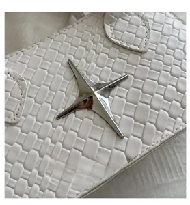 Detail of white woven leather texture with a silver star metal emblem on the bag