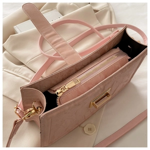 Detail view of pink baguette bag showing gold buckle and internal zipper pouch
