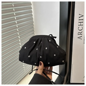 Detail of black polka dot crossbody bag featuring ruched texture and drawstring closure