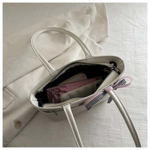 Detailed interior of a white tote bag featuring pink plaid bow and zip compartments