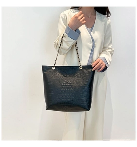Close-up of black crocodile pattern faux leather tote bag with metal chain strap detail