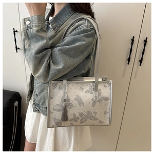 Detail of grey butterfly print shoulder bag with silver trim and tassel accessory