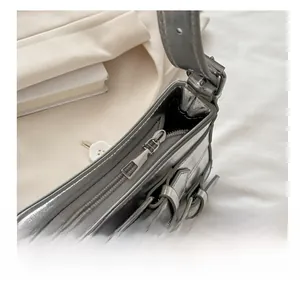 Detail view of smooth silver metallic shoulder bag with metal zipper and buckle