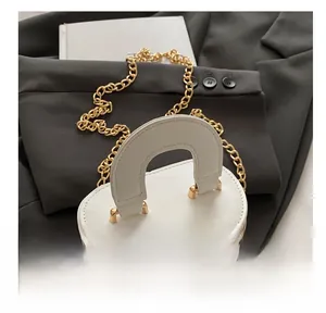 Détails d'un mini sac seau blanc avec poignée ronde et bandoulière dorée
