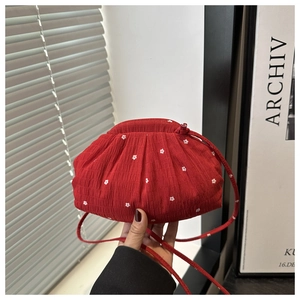 Detail showing red floral cloud bucket bag with pleated texture and thin shoulder strap