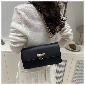 Détail d'un sac baguette chic en cuir noir avec chaîne dorée porté par un mannequin
