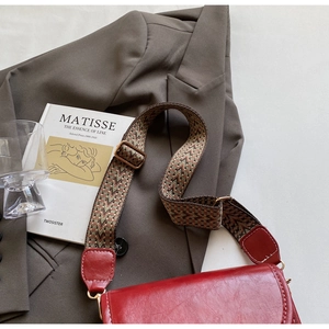 Close-up of red oil leather saddle bag with wide retro strap and white stitching