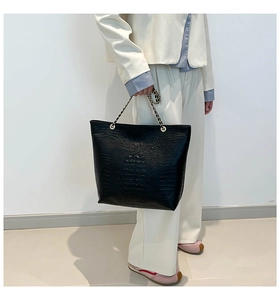 Detail of black embossed tote bag with metal and leather woven chain handles