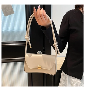Detailed view of cream PU leather shoulder bag with golden buckle and knotted straps