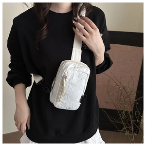 Detail of off-white nylon crossbody bag with wrinkled texture on a model in black