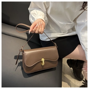 Detailed view of brown leather bag with a vintage gold metal twist lock and shoulder strap