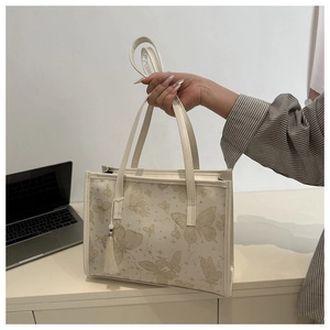 Detailed view of white butterfly print tote bag with elegant tassel and long handles