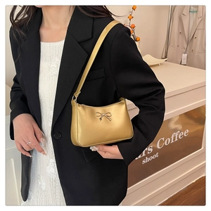 Close-up of golden bow-shaped metal buckle on a metallic patent leather shoulder bag