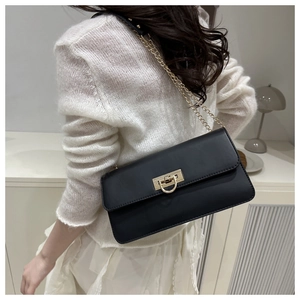 Vue latérale du sac baguette en cuir noir avec boucle dorée en U et bandoulière