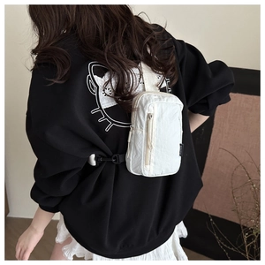 Detail der weißen Nylon-Brusttasche mit Fashion-Label und schwarzem Tragegurt