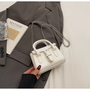 Detailed view of white mini chain handbag with silver buckle on elegant blazer backdrop