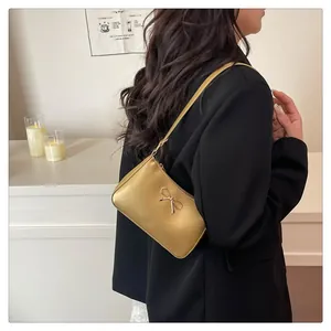 Detail of matte gold shoulder bag with metallic bow buckle and zipper closure