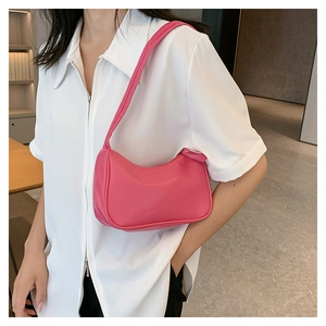 Detail shot of a candy pink mini crescent hobo bag worn by a model in a white shirt
