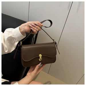 Detail of vintage brown baguette bag featuring a metallic gold twist-lock closure